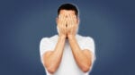 Life Sucks Man in White Shirt Holding Hands Over Face Blank Background