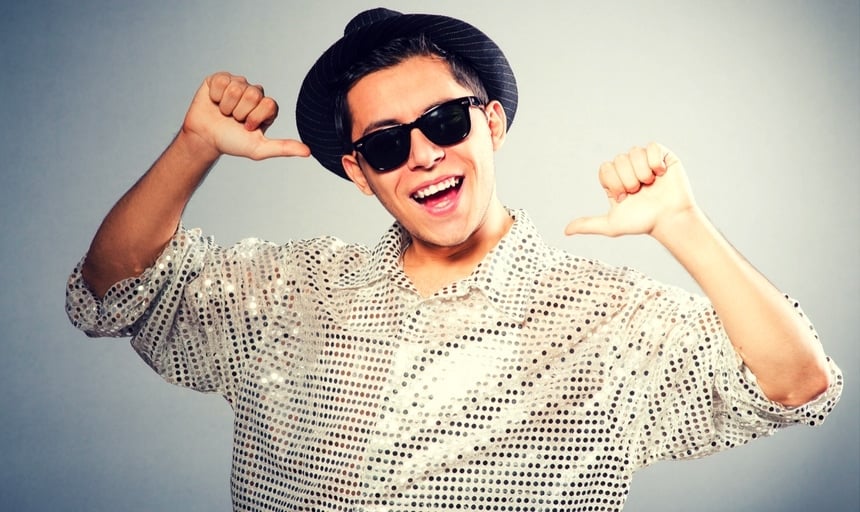 Man with shiny shirt and fedora pointing to himself and smiling 2