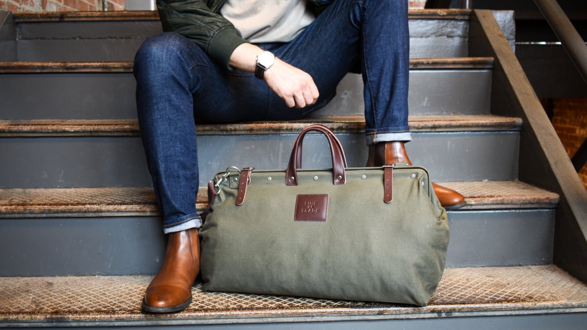 Mens Accessories Stylish Model Sitting on Steps with Weekender Bag and Watch Showing