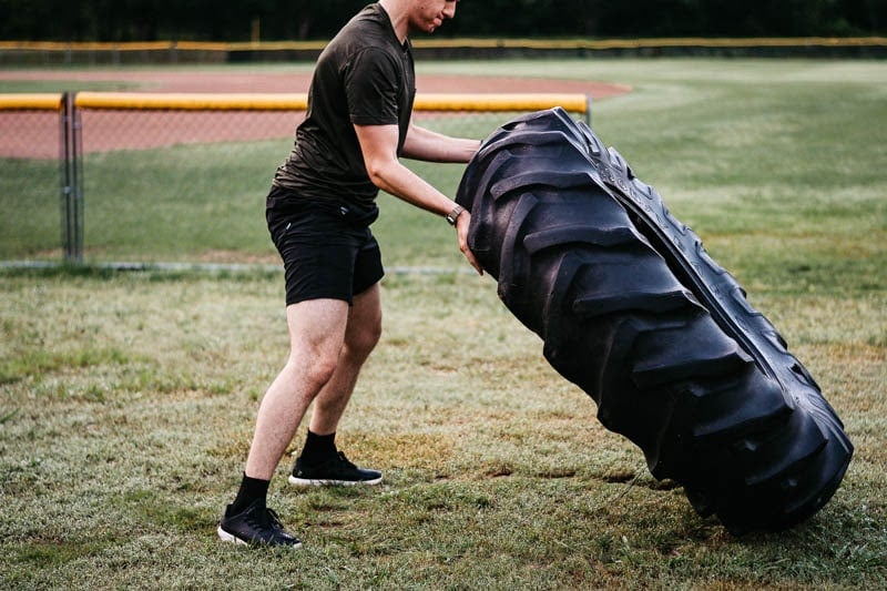 model wearing vuori kore shorts and tradewind tech tshirt and flipping tire